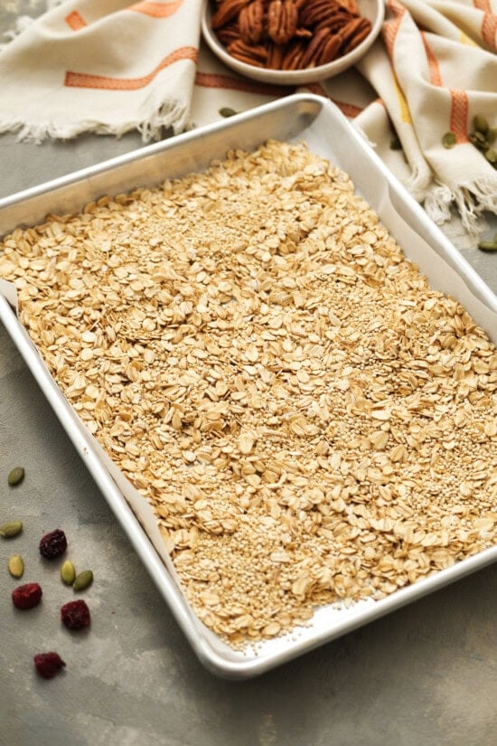 Homemade pumpkin granola with pumpkin, oats, quinoa and flax seed. It's sweetened with maple syrup, has the perfect amount of pumpkin spice! Oats on a sheet pan to make granola