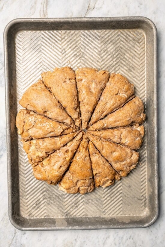 Buttermilk gives these spiced apple scones a moist, tender crumb, while applesauce replaces much of the butter to lighten them up! Overhead view of baked apple scones on baking sheet