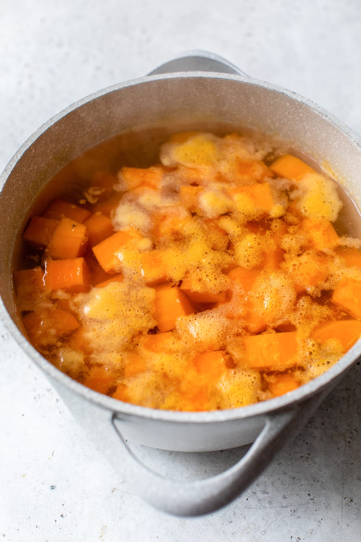 These buttery mashed sweet potatoes are a fluffy, creamy, and delicious side dish recipe. Ready in 25 minutes and made without sugar! Cubed sweet potatoes boiling in a pot of water.