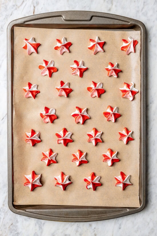 Light and airy peppermint meringues are the perfect addition to any holiday cookie tray! They're surprisingly easy to make and always a hit. Overhead view of peppermint meringues on parchment-lined pan before baking