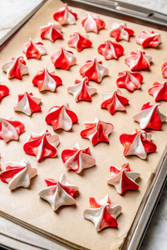 Light and airy peppermint meringues are the perfect addition to any holiday cookie tray! They're surprisingly easy to make and always a hit. Peppermint meringues on parchment-lined pan