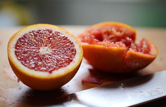 Two halves of a blood orange, with one half squeezed