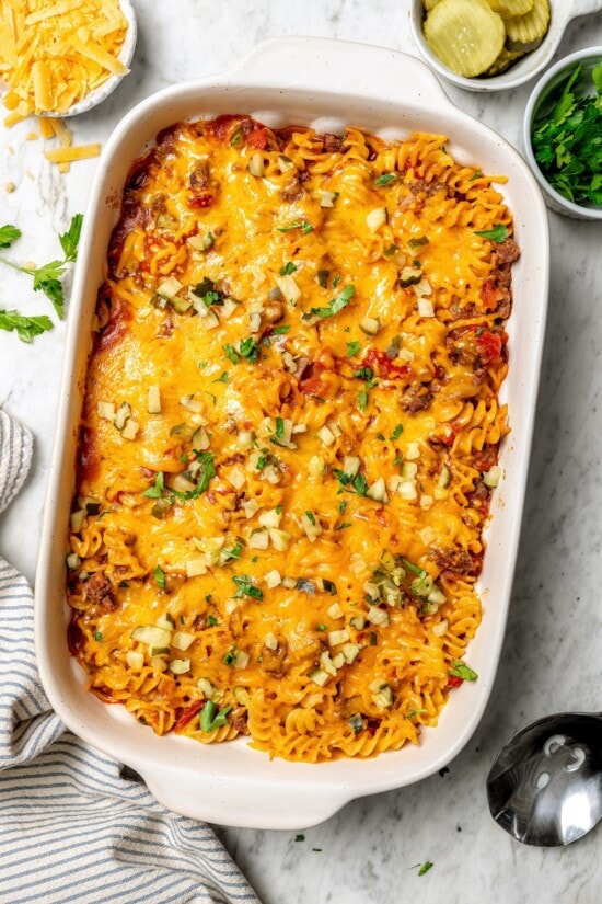 With ground beef, tomatoes, pickles, and cheese, this lightened up cheeseburger casserole recipe is kid-friendly and so delicious! Overhead view of cheeseburger casserole in baking dish