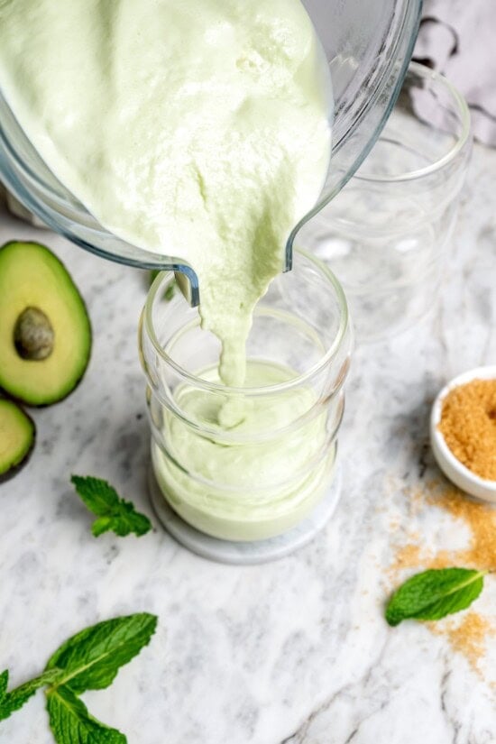 This easy homemade shamrock shake recipe is thick, creamy, and minty just like the original—with a fraction of the calories! Pouring shamrock shake into glass