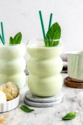 Skinny shamrock shakes in glasses with straws and fresh mint leaves