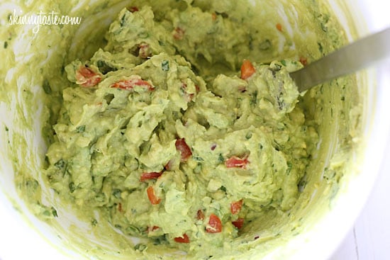 Guacamole prep with mashed avocado, cilantro and lime juice.