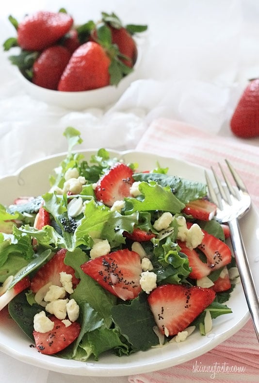Strawberry salad made with mixed greens, kale and spinach, sliced almonds, crumbled gorgonzola cheese and topped with poppy seed dressing – perfect for summer!