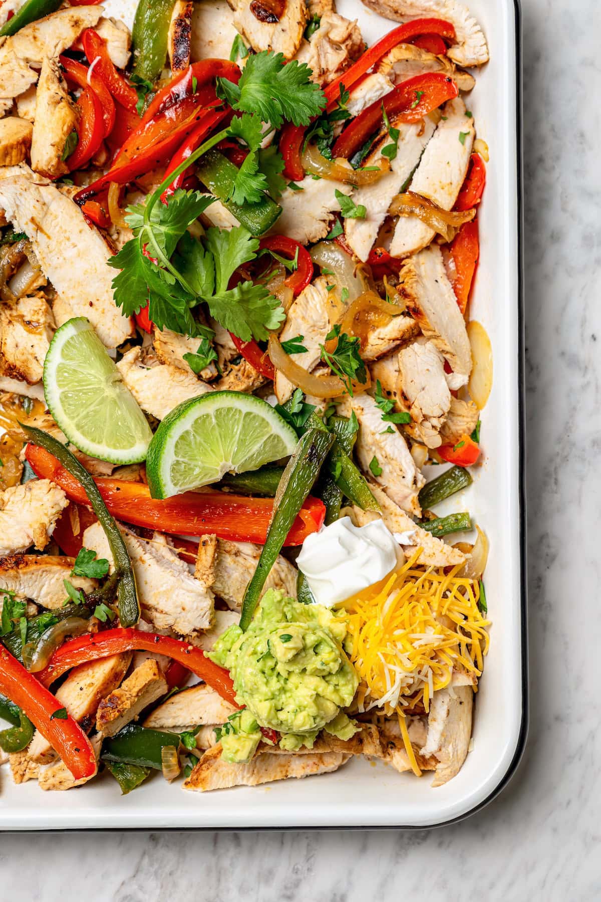 These easy chicken fajitas are made with grilled chicken breast, bell peppers and onions and served sizzling hot with tortillas and cheese! Overhead view of chicken fajitas in pan