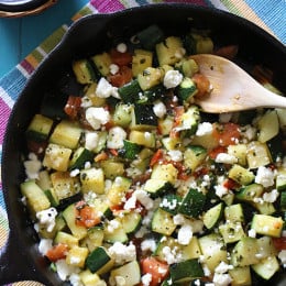 Mexican zucchini in a black cast iron skillet with a wooden spoon.