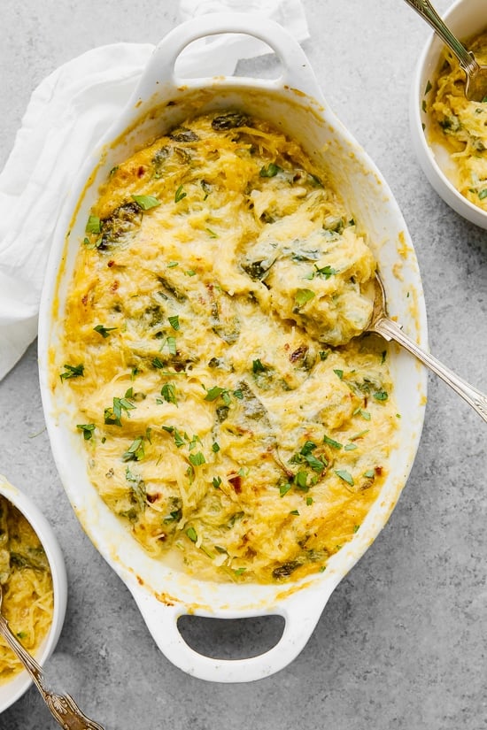 Casserole dish of cheesy baked spaghetti squash with green vegetables