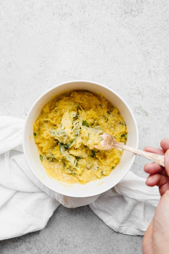 Bowl of cheesy baked spaghetti squash with green vegetables