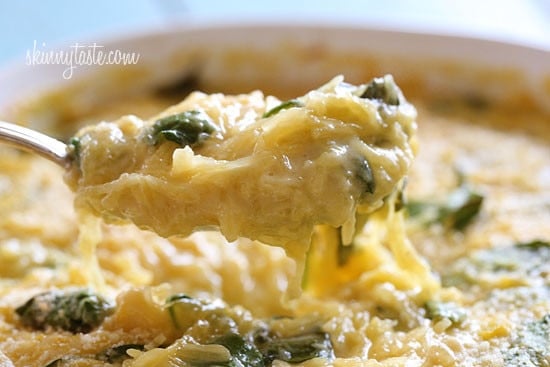 A bowl of creamy spaghetti squash with pieces of spinach