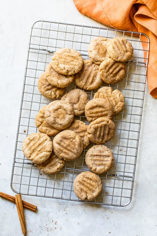 A simple sugar cookie dough is rolled in sugar and pumpkin pie spice to make these soft and chewy Pumpkin Snickerdoodles. Pumpkin snickerdoodle cookies on a wire rack