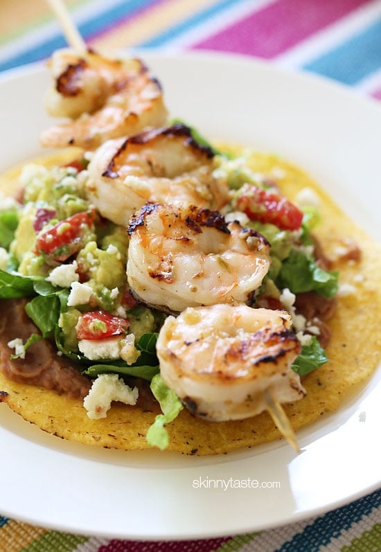 Grilled Shrimp Tostadas are SO good, layered with homemade guacamole, refried beans and lettuce on top of a crispy tostada.