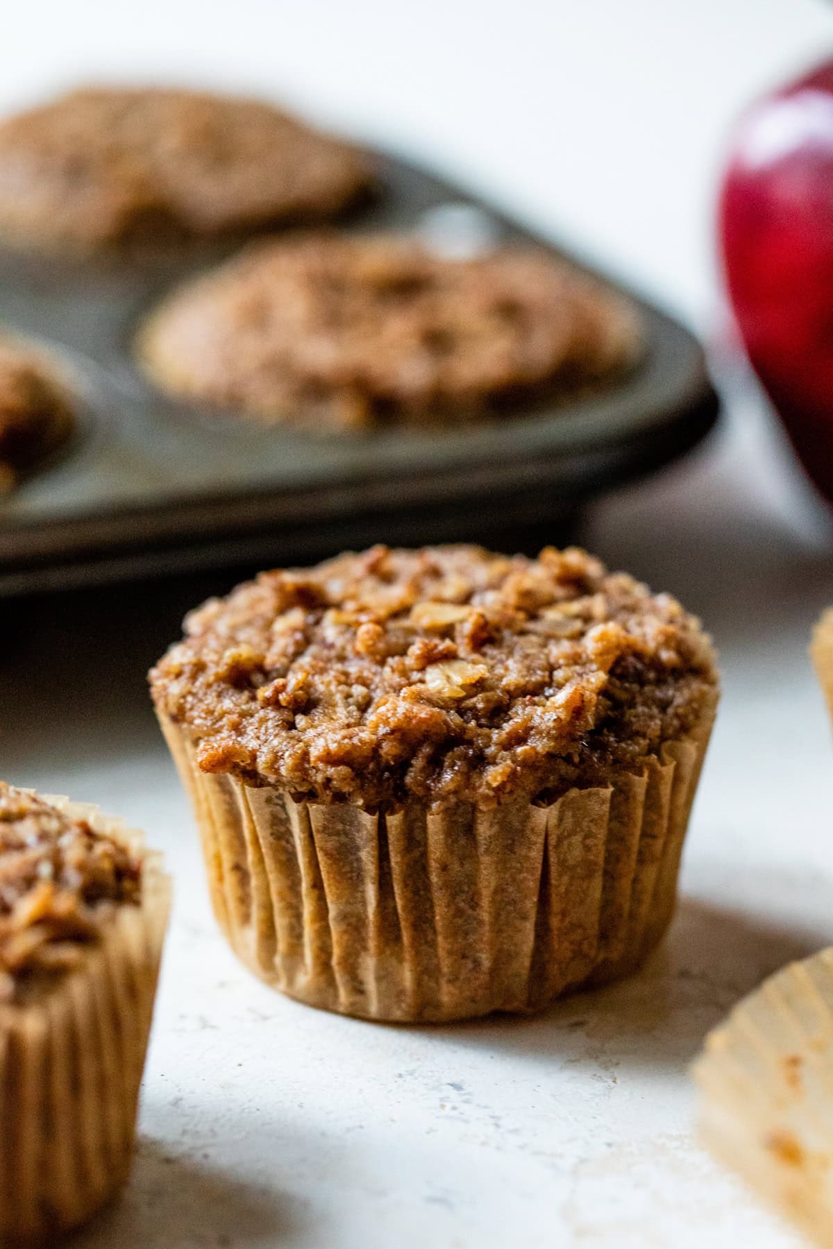 These apple cinnamon muffins are packed with sweet apples, crunchy walnuts, and a hint of spice. Add granola on top for a bit of crunch! Healthy Apple Muffins on a counter.