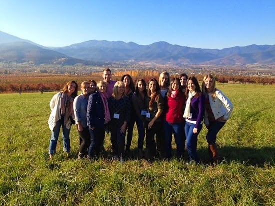 A group of friends in a field with fall foliage and mountains behind them
