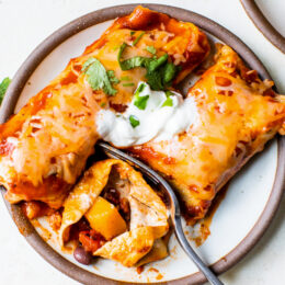 Easy vegetarian enchiladas made with butternut squash and black beans, smothered with enchilada sauce and cheese, then baked in the oven. A delicious recipe that's perfect for meatless Mondays!