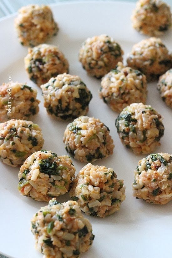 A plate of brown rice balls with crumbled sausage and pieces of spinach