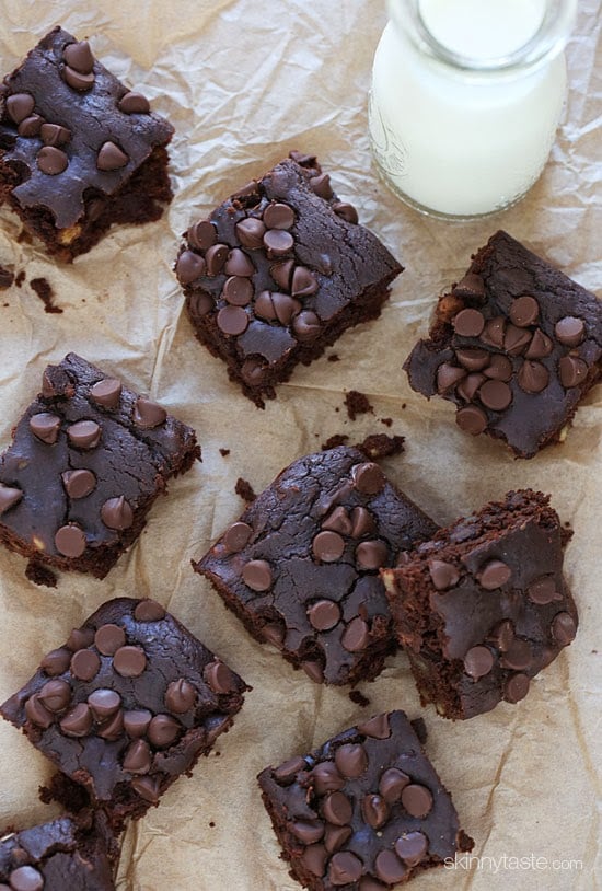 Overhead view of black bean brownies on parchment paper with glass bottle of milk