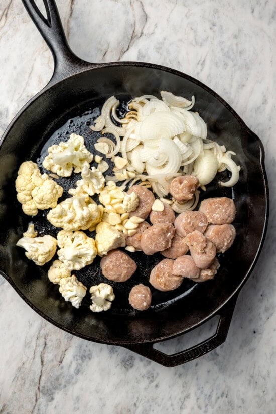 Cauliflower and chicken breasts make this Chicken Scarpariello recipe low carb, but it's just as spicy and flavorful as the classic version! Sausage, cauliflower, and onions added to cast iron skillet.