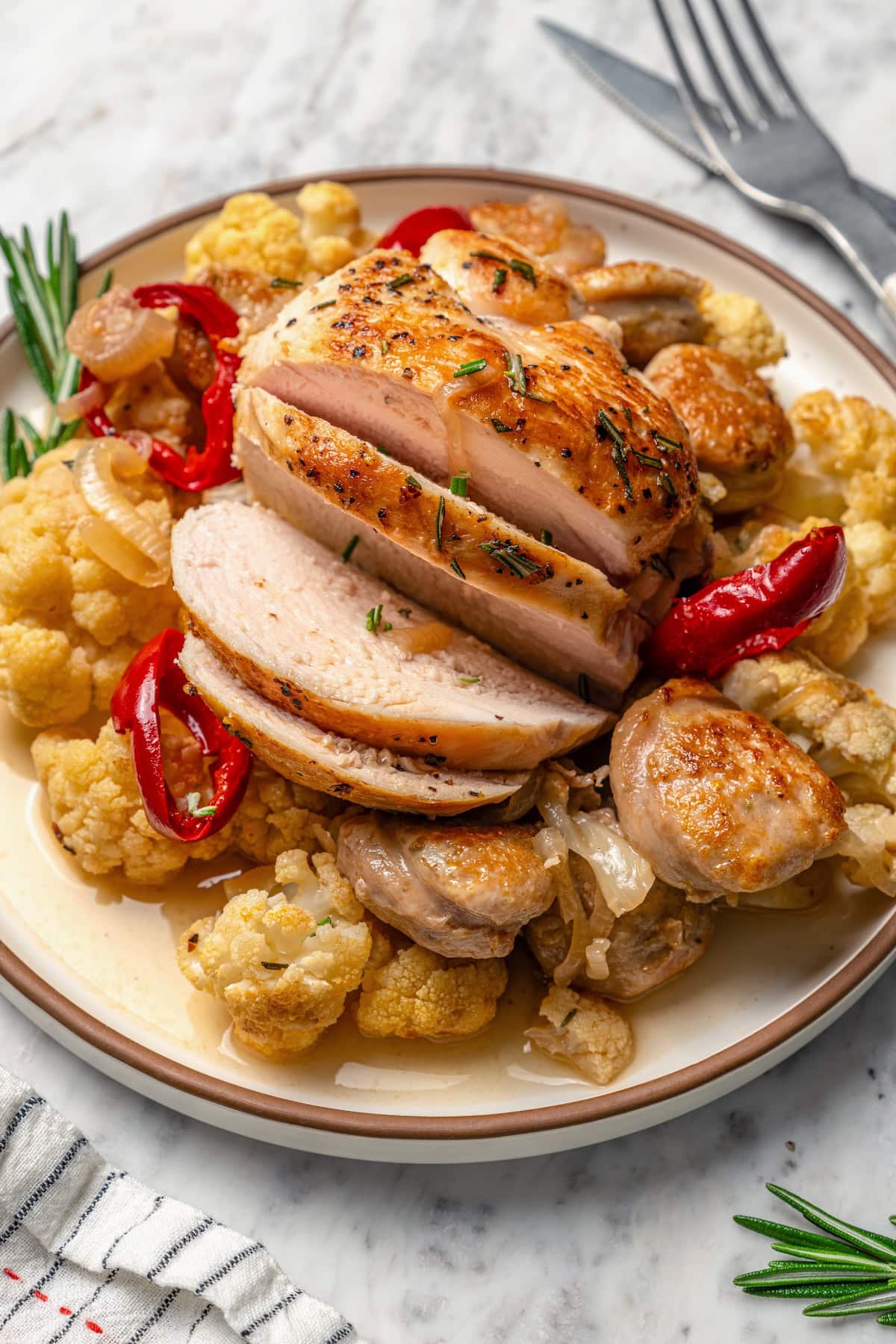 Cauliflower and chicken breasts make this Chicken Scarpariello recipe low carb, but it's just as spicy and flavorful as the classic version! Sliced chicken scarpariello on plate with sausage and cauliflower.