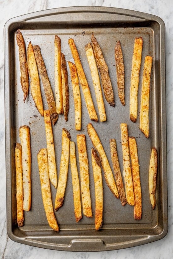 This lightened up Peruvian lomo saltado recipe is packed with flavor, with tender sirloin and veggies served alongside crispy baked fries. Overhead view of baked fries on sheet pan