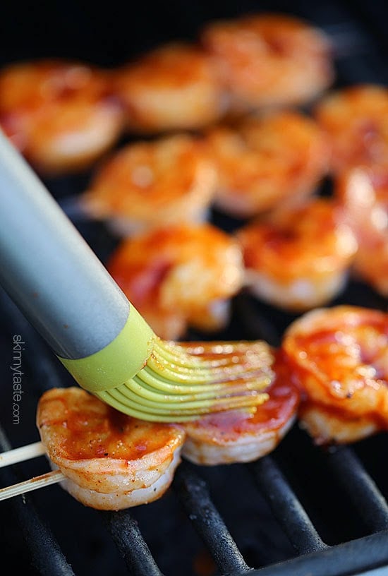 brushing bbq sauce on shrimp skewers