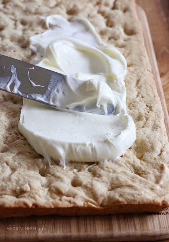 Red, White and Blue fruit "pizza" is more like a cookie bar, topped with cream cheese frosting and fruit – The perfect 4th of July dessert!