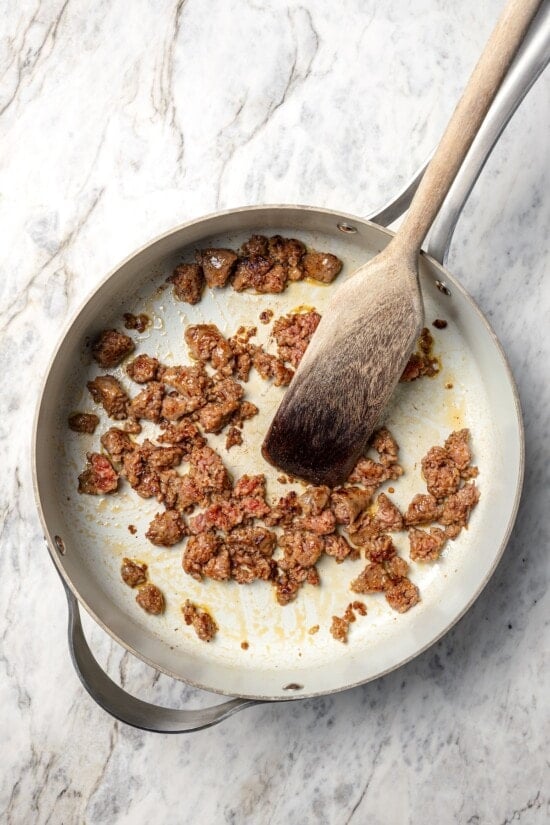 This healthy breakfast casserole recipe with sausage, cheese and veggies is hearty, flavorful, and perfect for meal prep or a weekend brunch! Sausage browning in skillet.