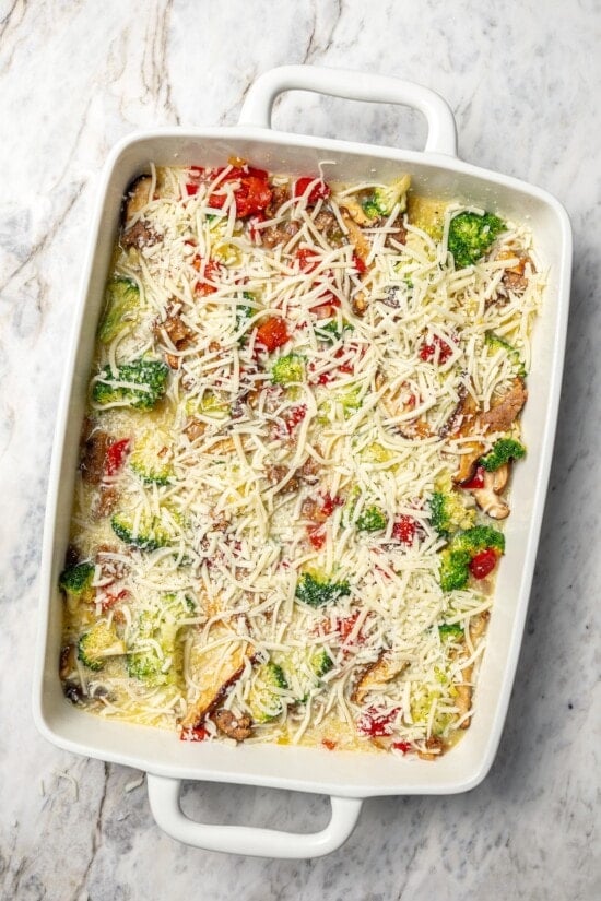 This healthy breakfast casserole recipe with sausage, cheese and veggies is hearty, flavorful, and perfect for meal prep or a weekend brunch! Breakfast casserole in baking dish before baking.