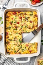 Breakfast casserole in baking dish with one portion removed.