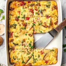 Breakfast casserole in baking dish with one portion removed.