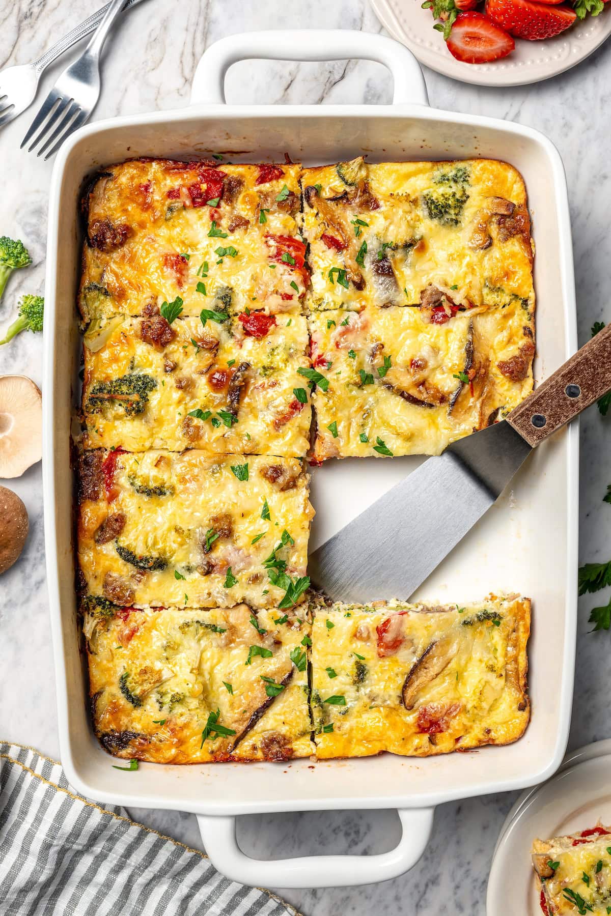 This healthy breakfast casserole recipe with sausage, cheese and veggies is hearty, flavorful, and perfect for meal prep or a weekend brunch! Breakfast casserole in baking dish with one portion removed.