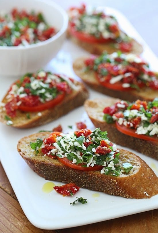 Super easy two tomato bruschetta made with roma and sun dried tomatoes, basil and feta cheese over toasted whole wheat bread.
