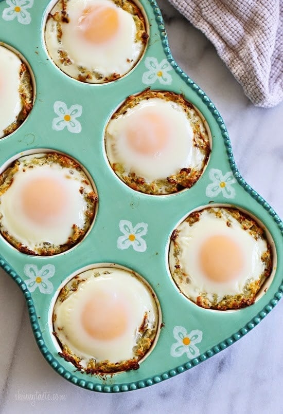 A muffin tin with a nest of spaghetti squash and a baked egg in each tin