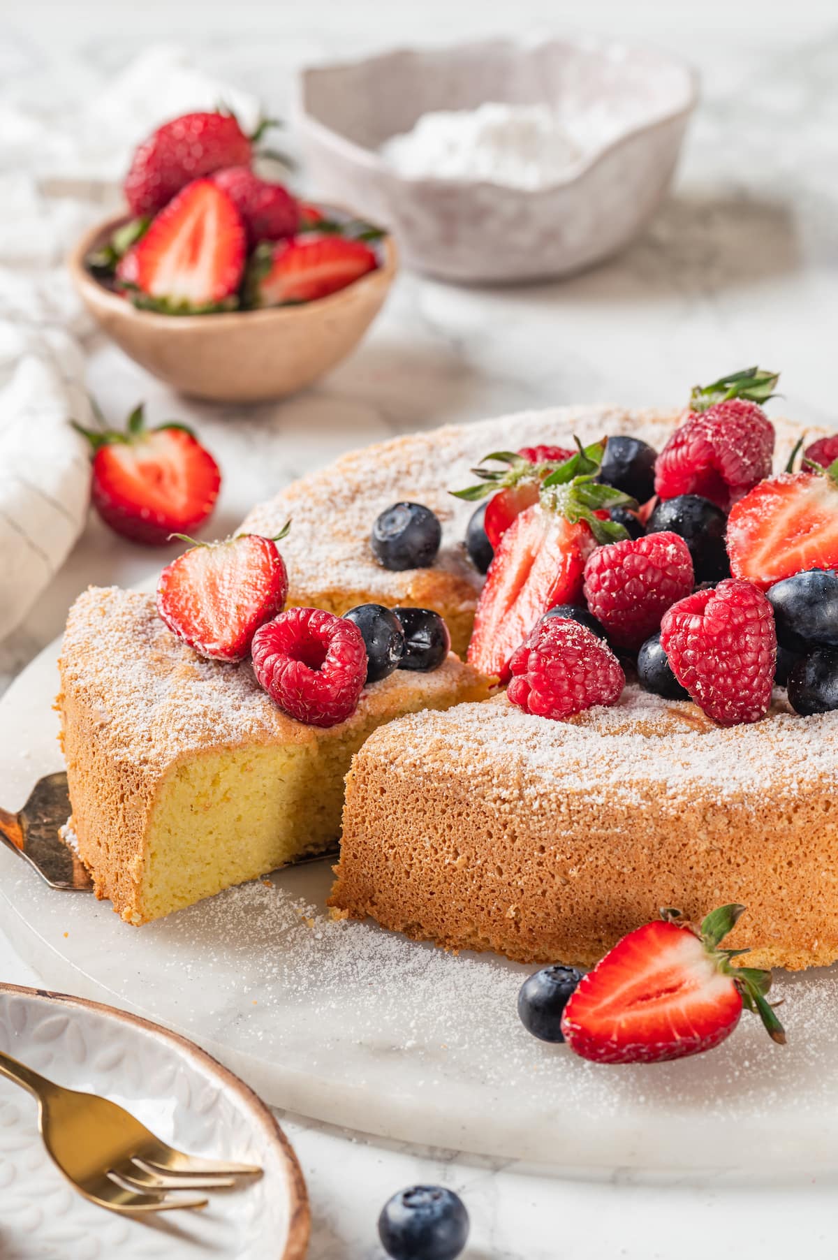This easy almond cake recipe is made with just 5 ingredients but don't let its simplicity fool you—it's light, airy, and so delicious! Removing slice of almond cake from platter