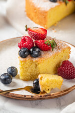 Almond cake on plate with fresh berries, with tip of cake on fork