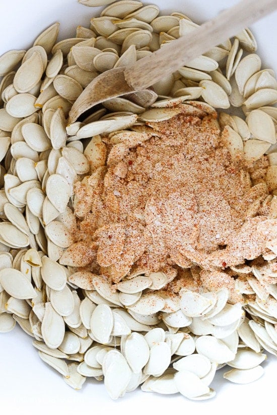 These Spicy Pumpkin Seeds are a fun twist on roasted pumpkin seeds. They make a tasty, filling snack on their own and a great salad topper. A seasoning mixture on top of pumpkin seeds in a bowl