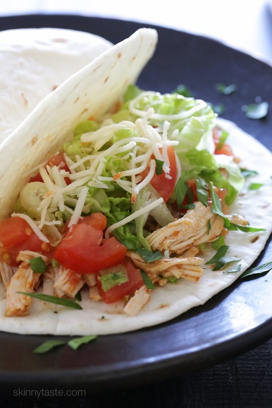 Instant Pot salsa chicken is so quick and easy! Make this juicy 2-ingredient shredded chicken to use in tacos, rice bowls, salads, and more. Instant Pot salsa chicken served in a flour tortilla with taco toppings.
