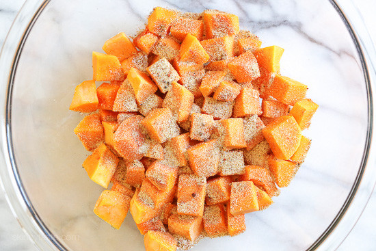 A mixing bowl of cubed butternut squash with spices