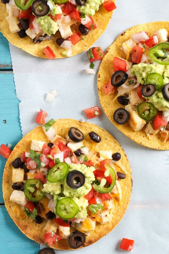 These easy loaded chicken "nacho" tostadas – topped with cheese, tomatoes, guacamole, olives and jalapenos are a great way to take nachos and turn them into a main dish.