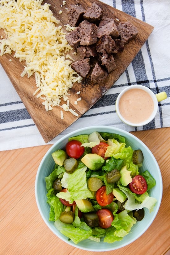 This salad has everything I love about a cheeseburger, sans the bun. Chopped romaine, tomatoes, avocado, pickles, shredded cheese topped with grilled burgers, red onions and drizzled with a seriously delicious dressing.