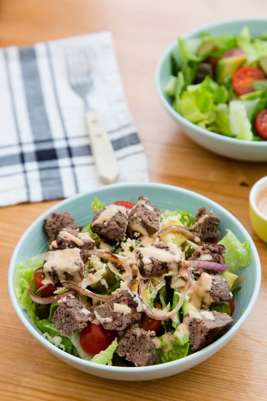 This salad has everything I love about a cheeseburger, sans the bun. Chopped romaine, tomatoes, avocado, pickles, shredded cheese topped with grilled burgers, red onions and drizzled with a seriously delicious dressing.