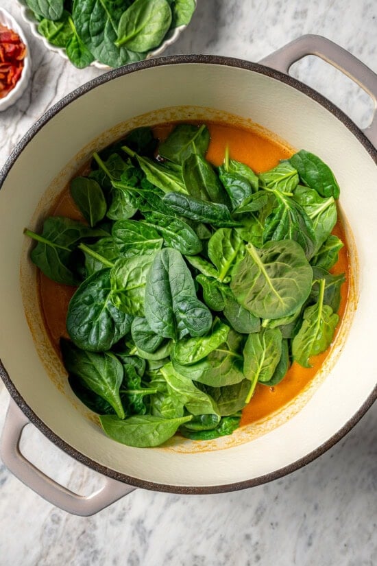 This delicious, hearty navy bean soup is inexpensive and easy to make! Cook it on the stovetop, or in your Instant Pot or slow cooker. Baby spinach added to pot of navy bean soup
