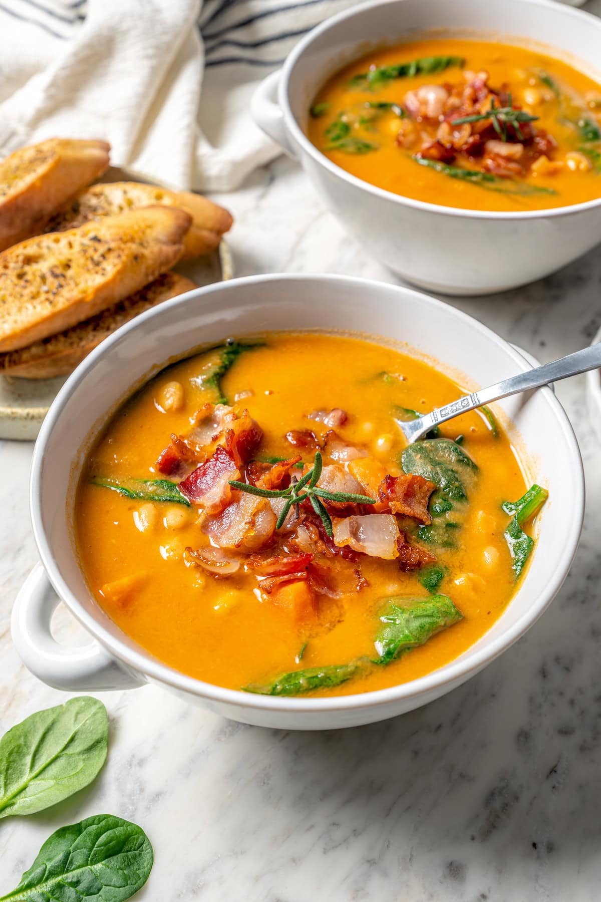 This delicious, hearty navy bean soup is inexpensive and easy to make! Cook it on the stovetop, or in your Instant Pot or slow cooker. Bowl of navy bean soup with bacon on top