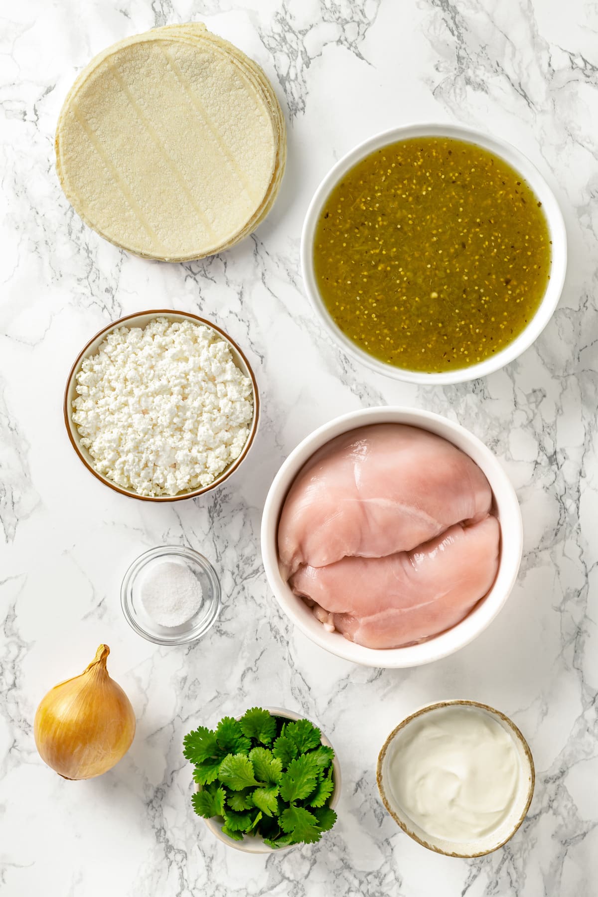 These Chicken Enchiladas Verdes (aka Green Enchiladas) are made with white corn tortillas, salsa verde, chicken breast, and queso fresco. Overhead view of ingredients needed to make enchiladas verdes