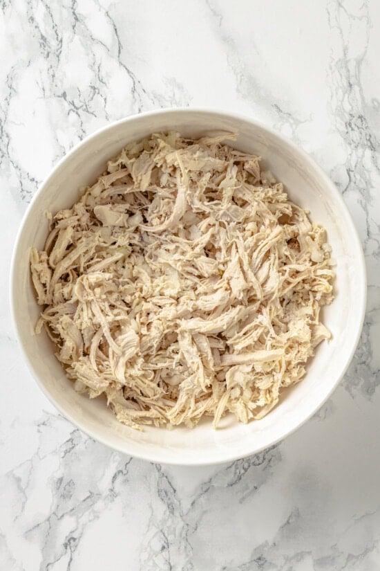 These Chicken Enchiladas Verdes (aka Green Enchiladas) are made with white corn tortillas, salsa verde, chicken breast, and queso fresco. Shredded chicken in a bowl