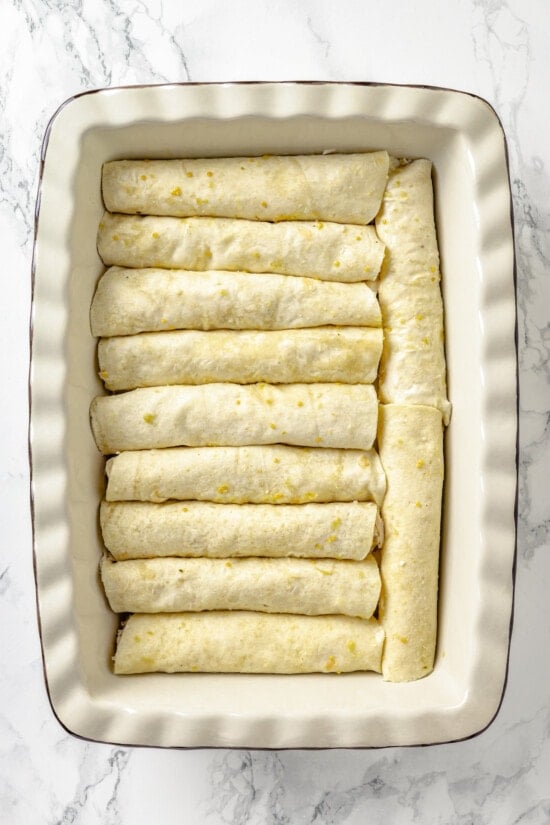 These Chicken Enchiladas Verdes (aka Green Enchiladas) are made with white corn tortillas, salsa verde, chicken breast, and queso fresco. Enchiladas rolled in a baking dish