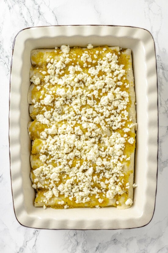 These Chicken Enchiladas Verdes (aka Green Enchiladas) are made with white corn tortillas, salsa verde, chicken breast, and queso fresco. Queso fresco on top of salsa verde on enchiladas
