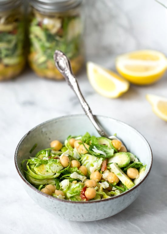 A quick and easy salad in a jar made with shaved Brussels sprouts, chickpeas, marinated artichokes, sun dried tomatoes and Asiago cheese. Perfect to pack for work or anywhere you need a portable lunch on-the-go! To serve you simply shake it up and pour it into a bowl.
